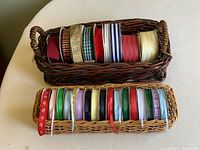Two baskets of assorted craft ribbons placed on a white surface, showing variety of colors and patterns