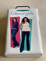 Front view of the Gilmore Girls Complete Series DVD set in a white case featuring main characters.