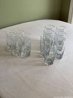 Photo showing all 12 glasses arranged on a light surface, 7 taller glasses grouped and 5 medium smaller glasses grouped.