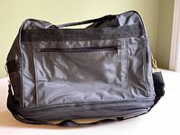 Side/angled view of the travel bag being held by the handles, highlighting size, structure, and zipper details.