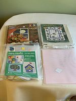 Bag of crafting projects including multiple plastic canvas needlepoint kits and extra plastic canvas.