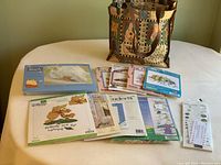 Bag of cross stitch kits and yarn project cards arranged on table showing full lot contents