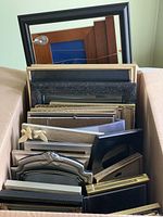 Photo of multiple picture frames stacked vertically showing various sizes and materials including wood and metal
