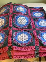 Overview of quilt top showing multiple sewn blocks with floral hexagons and colorful borders.