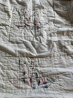 Close-up of the patchwork quilt design side showing intricate stitching and mixed fabrics forming square blocks.