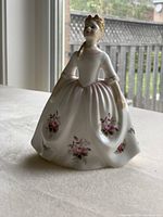 Front view showing the delicate pink and lavender rose floral decorations on the white dress of the Royal Doulton figurine.