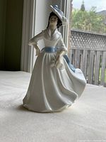 Front view of Royal Doulton 'Margaret' porcelain figurine showing full figure in white dress with blue sash and bonnet.