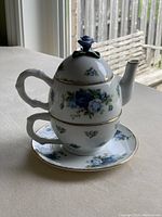 Photo of the assembled teapot with the cup stacked beneath showing overall shape and decorative details.