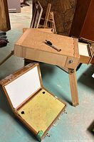 Wooden art box with hinged lid open, yellow stained inside, white interior lid, and metal clasps