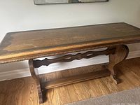 Full view of the long rectangular wood table showing carved edging and overall shape.