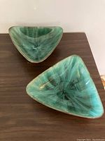 Two triangular Blue Mountain Pottery bowls seen from a downward angle showing turquoise-green swirling glaze inside and brown exterior.