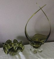 Large khaki and clear glass centrepiece bowl with curving extended handles on white surface