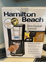 Front view of unopened box of Hamilton Beach BrewStation Summit 12 Cup Coffeemaker showing product features and image of the coffee maker with thermal carafe.
