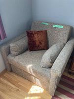 Front view of the upholstered chair with a brown throw pillow in place.