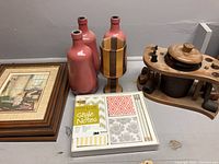 Image showing framed prints, ceramic vases including a wooden striped vase, a boxed set of new stationery, and a wooden pipe stand with tobacco jar.