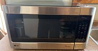 Front view of the LG microwave showing stainless steel finish, black window, and control panel on the right.