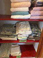 Photo showing pillow cases with floral patterns and additional bedding items folded on shelves.