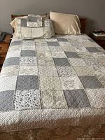 Full bed setup showing patchwork quilt, pillows and headboard