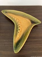 Full top view of the triangular yellow glazed pottery ashtray with green and dark brown drip accents.