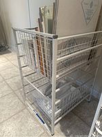 Front and side angle view of white wire basket unit showing the two baskets loaded with papers and books.