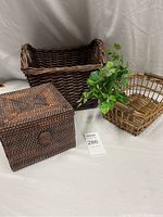 Photo showing three rattan items: dark brown woven box with lid, large dark brown basket, smaller light brown basket with handle