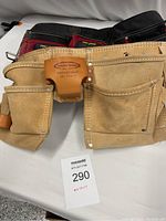 Wide view of two handmade heavy suede work aprons with multiple pockets, showing the front and upper belts area.