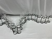 Front angled view showing the entire length of the candle holder with multiple glass containers and black rings on metal frame