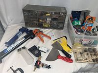 Photo of whole tool set including caulking guns, putty knives, grease gun, small spray bottle, and plastic organizer with screws and fasteners, plus plastic bin with adhesives and extra tools.