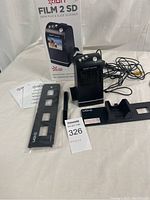 Full lot showing the Ion Film 2 SD scanner device, its original box, power cord, film strip holder, slide holder, and a manual.