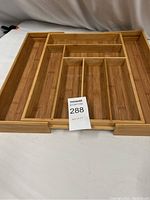 Front view of natural bamboo expandable flatware organizer showing various compartments for utensils and cutlery.