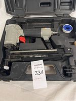 Porter Cable FN250SB finish nailer inside molded plastic case with roll of Teflon tape, showing tool color and accessories included.