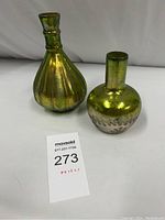 Two green iridescent mercury glass vases shown side by side on white background, displaying shapes and reflective surfaces.