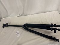 Full view of Slik The Professional tripod on white sheet, showing extended legs with foam grips and locking mechanisms.