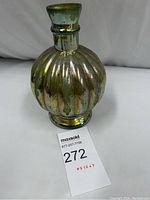 Photo showing full view of vintage mercury glass vase with ribbed body and narrow neck, placed on white fabric background with auction card.