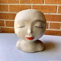 Front view of artistic head vase showing closed eyes and red lips.