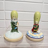 Two cookie press molds with fairy tale character handles: a child clinging to a stalk and a cat dressed as a prince.
