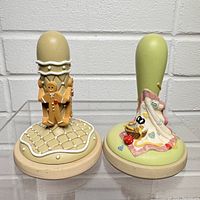 Two ceramic cookie press holders with decorative holiday designs, placed side by side.