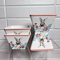 Four square ceramic Easter baskets stacked with bunny and floral artwork visible.