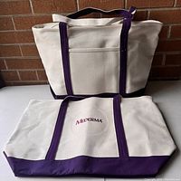 Two new Lands' End canvas tote bags with Mederma logo, purple straps and trim, cream canvas body shown from front and laying flat.