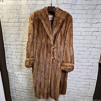 Front view of vintage ladies 3/4 length fur coat showing button closures and turned-back cuffs.