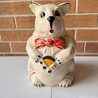 Front view of the vintage McCoy bear cookie jar with painted red bow tie and bear holding a cookie.