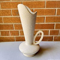 Front and side views of the vintage mid-century modern ceramic pitcher against a brick wall background.