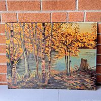 Full view of oil painting showing autumn birch trees by water with tree stump and vibrant orange and yellow leaves.