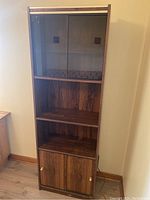 Full-front view of the tall brown laminate bookshelf showing three shelves and cupboard at base.