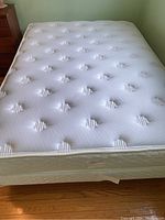 Full view of double bed mattress showing quilted padded surface and tufted design