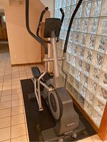 Elliptical machine showing side profile with sturdy frame and foot pedals on black mat.