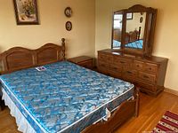 Overall view of bedroom set showing bed with mattress, two night tables, dresser with tri-fold mirror