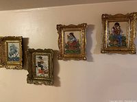Wide shot of five framed cross stitch wall decorations arranged in a row