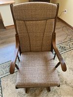 Front view of dark wood glider rocking chair with brown fabric upholstery on seat and backrest, showing padded seat cushion and armrests.