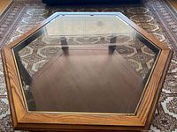 Top view of hexagonal coffee table showing clear beveled glass top with wooden frame and lower wood shelf.